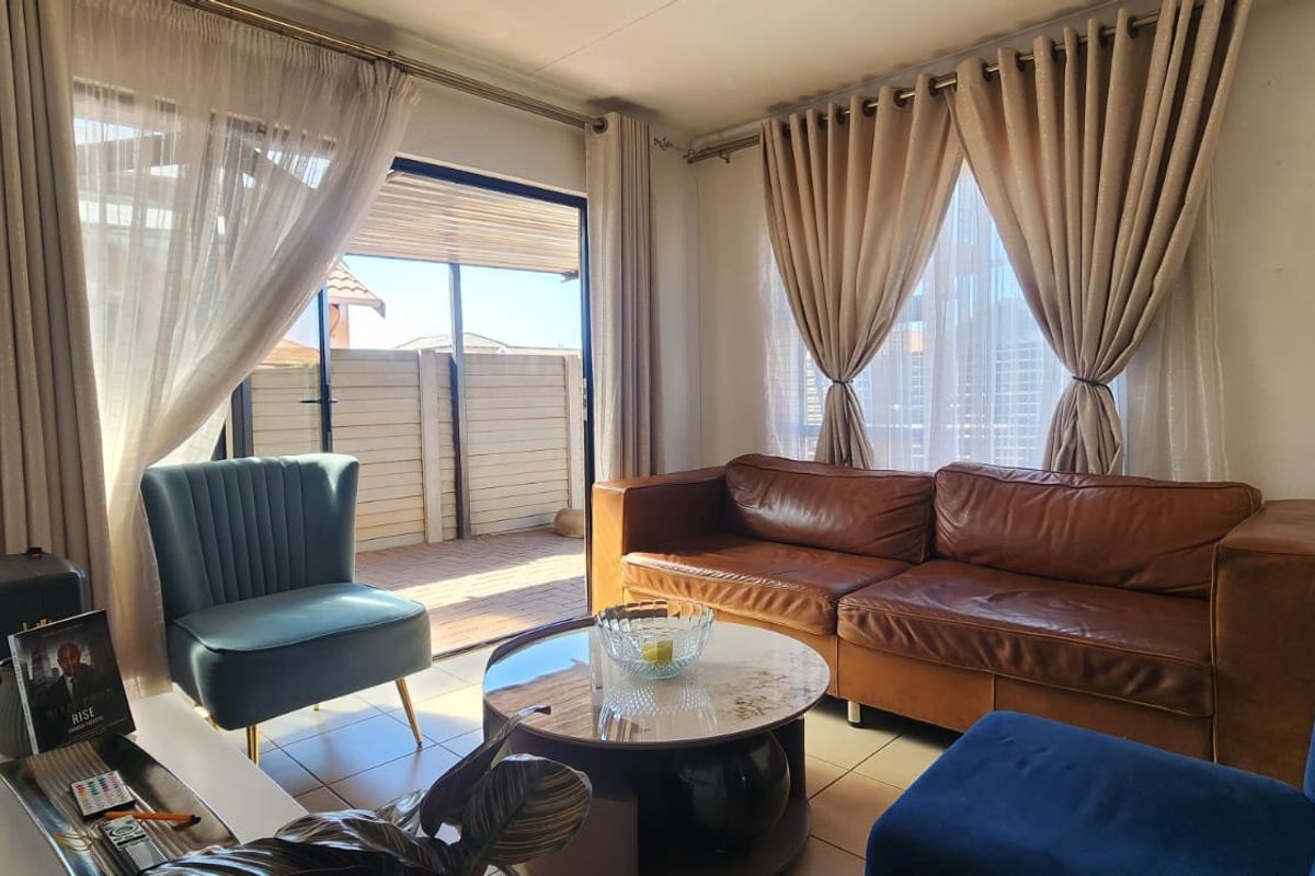 A comfortable living room featuring tiled flooring and a large sliding glass door that provides direct access to an outdoor patio area.