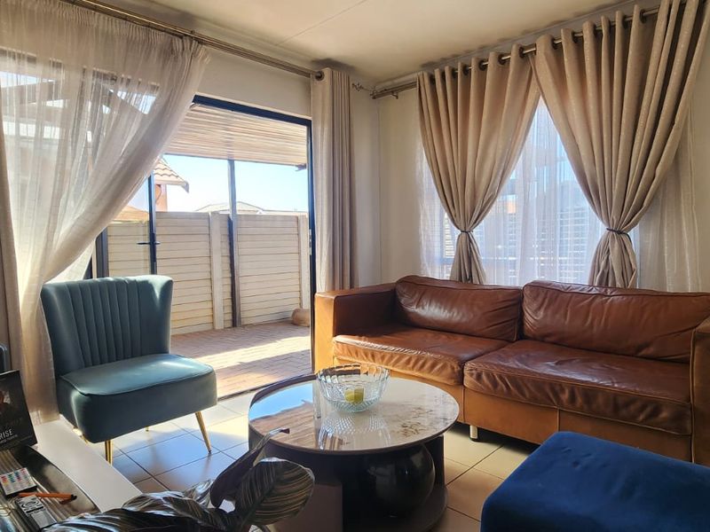 A comfortable living room featuring tiled flooring and a large sliding glass door that provides direct access to an outdoor patio area.