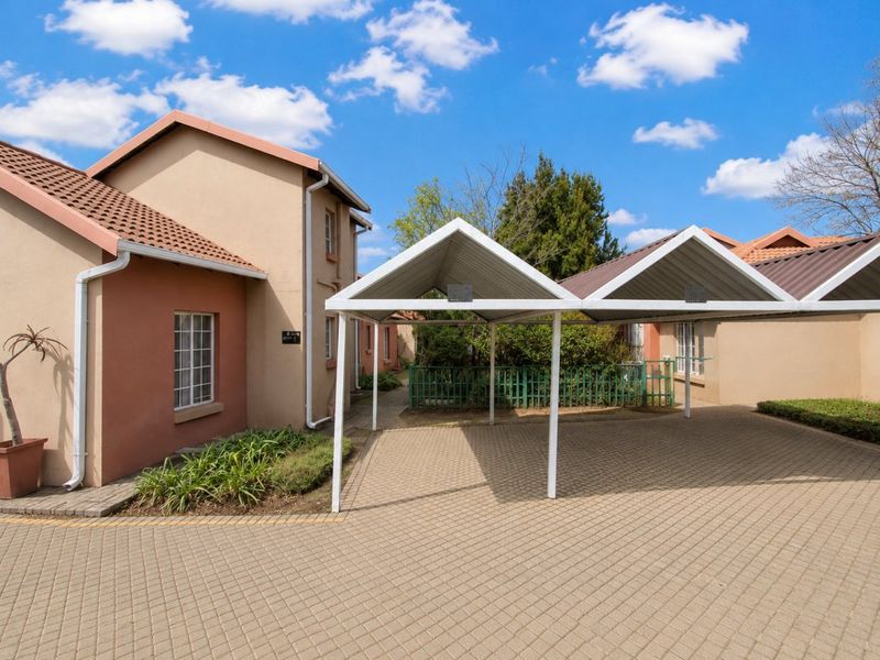 Exterior view of the apartment complex featuring a paved driveway and covered carport parking area.
