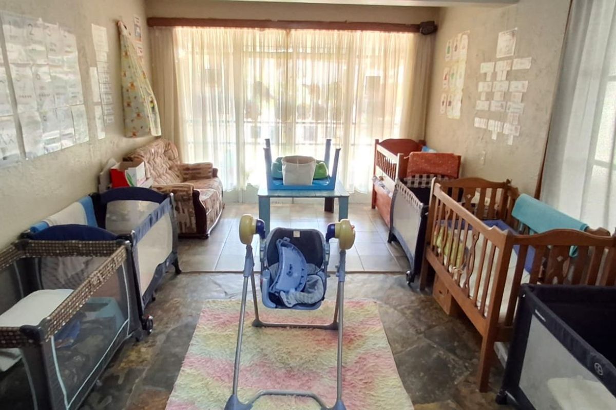 A multi-purpose room featuring tiled flooring and large sliding glass doors, currently utilized as a nursery space with natural light.
