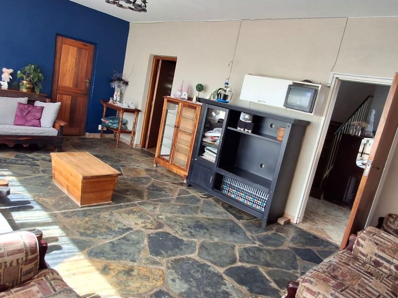 Spacious living room featuring rustic stone flooring and a bold accent wall, offering a versatile layout for comfortable family living.