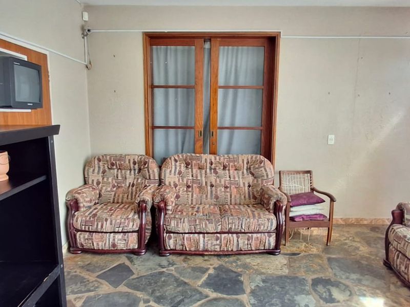 A living room featuring rustic stone flooring and wooden sliding doors, offering a dated aesthetic with potential for modernization.