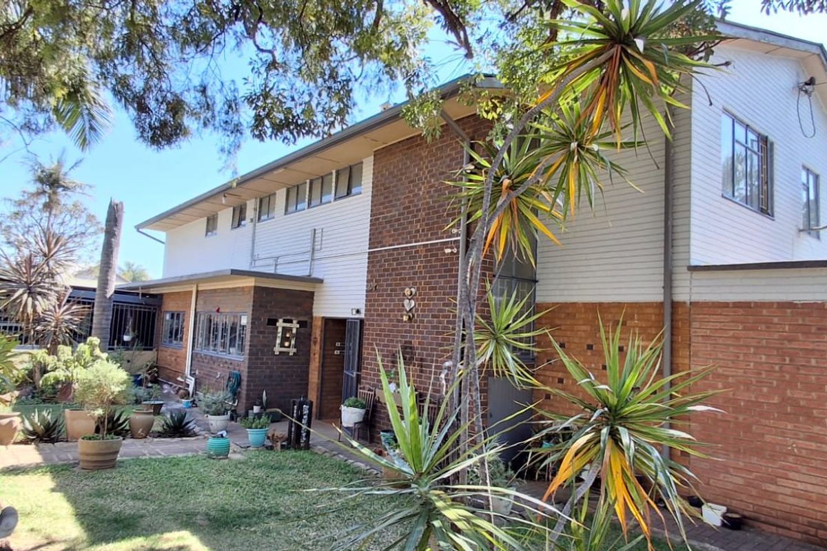 Rear view of a two-story residential property featuring a combination of brick and weatherboard cladding with established garden surroundings.
