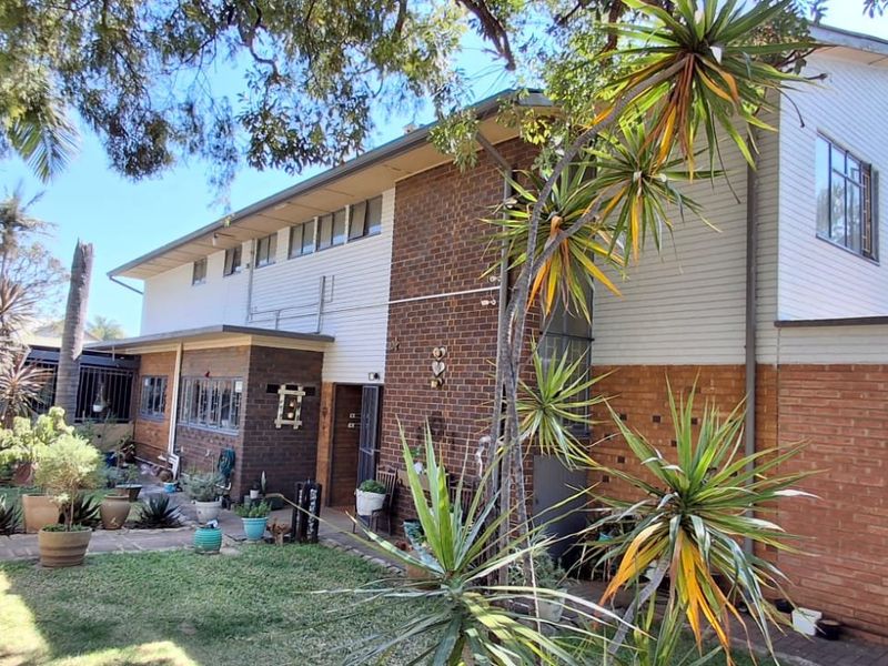 Rear view of a two-story residential property featuring a combination of brick and weatherboard cladding with established garden surroundings.