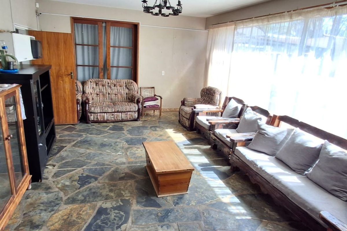 Spacious living room featuring natural slate flooring, large windows allowing ample natural light, and classic sliding door access.