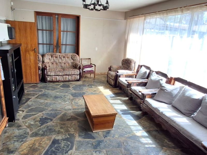 Spacious living room featuring natural slate flooring, large windows allowing ample natural light, and classic sliding door access.