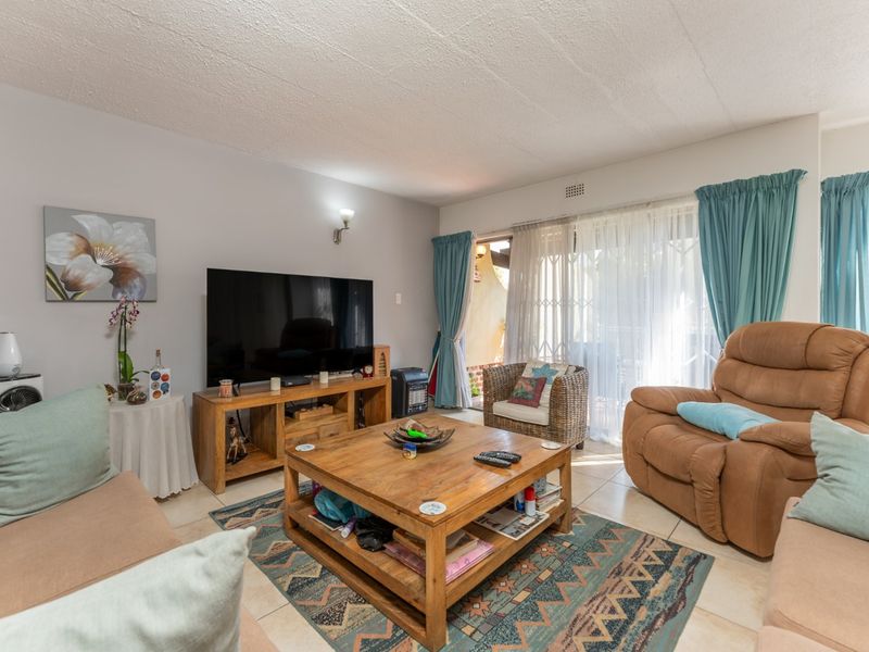 A comfortable living room featuring tiled flooring and a sliding glass door that provides access to the outdoor patio area.