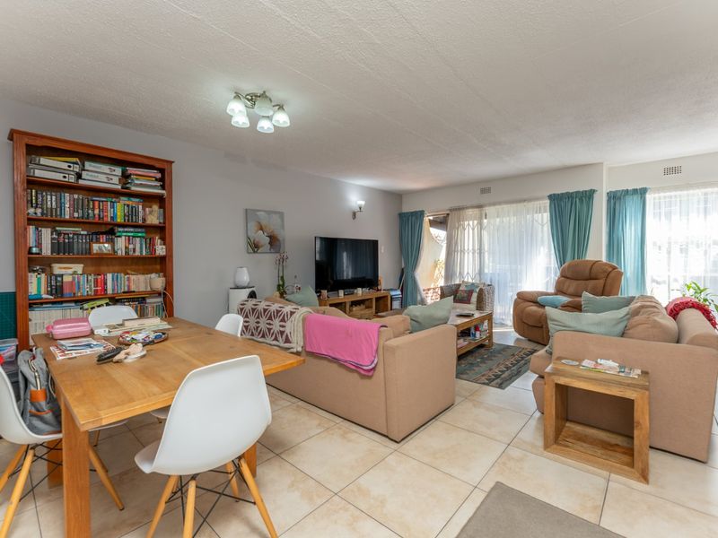 Spacious open-plan living and dining area featuring neutral ceramic floor tiles and large sliding glass doors providing access to the outdoor space.