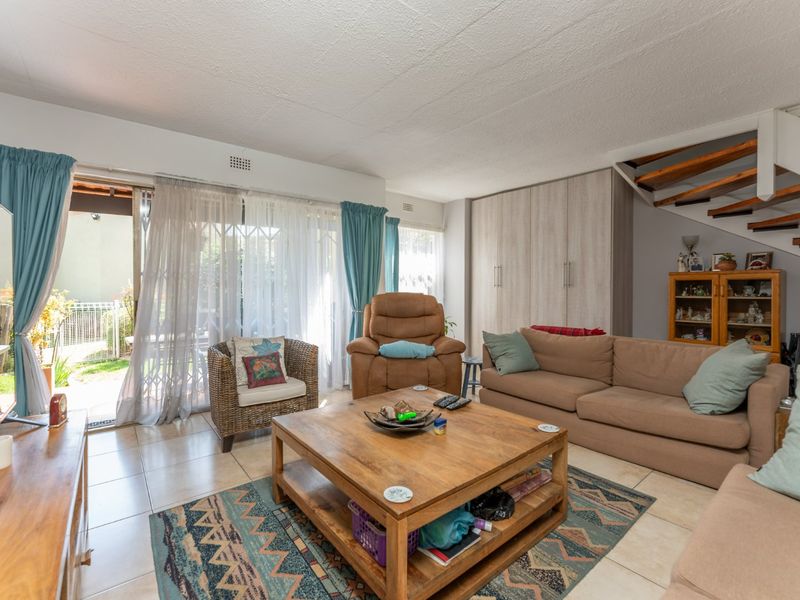 Spacious living room featuring tiled floors, built-in storage cupboards, and direct access to the outdoor patio area via sliding glass doors.
