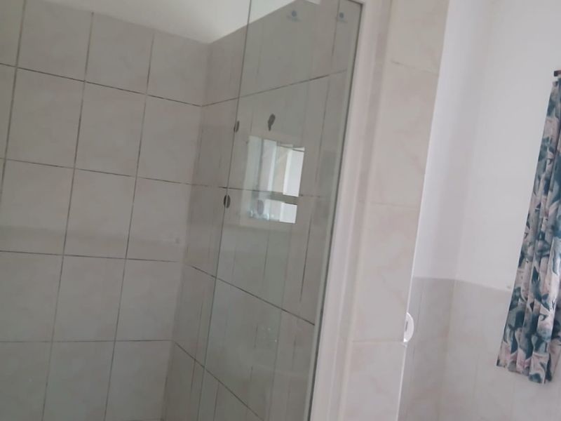 A functional bathroom featuring a glass shower enclosure and tiled walls, providing a clean and practical space.