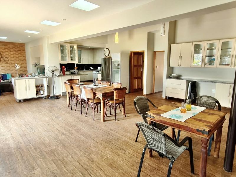 Spacious open-plan living and kitchen area featuring laminate flooring, built-in cabinetry, and an exposed brick feature wall.