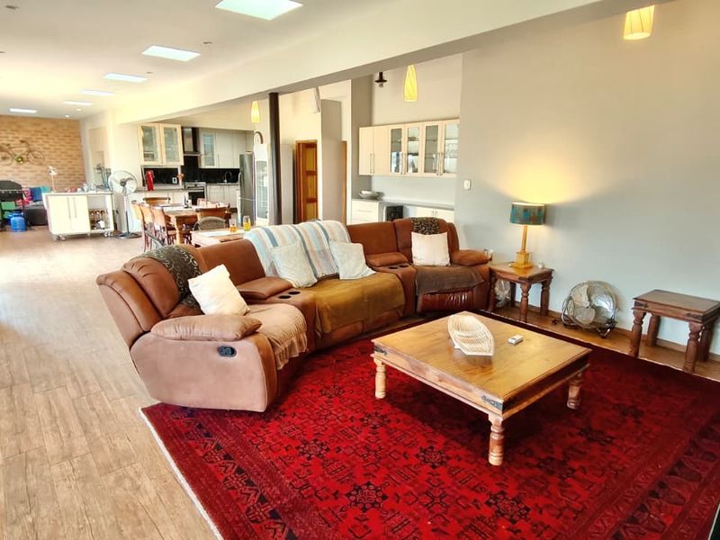 Spacious open-plan living area featuring tiled floors, multiple skylights, and a connected kitchen space with built-in cabinetry.