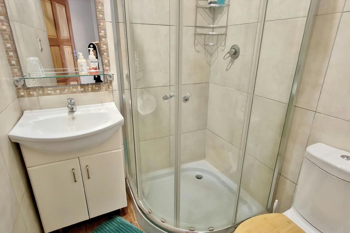 Compact bathroom featuring a corner shower enclosure, vanity cabinet with basin, and a standard toilet with neutral wall tiling.