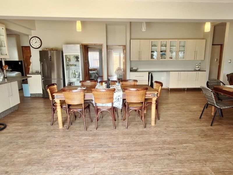 Spacious open-plan living and dining area featuring light-toned built-in cabinetry, laminate flooring, and a functional kitchen layout.
