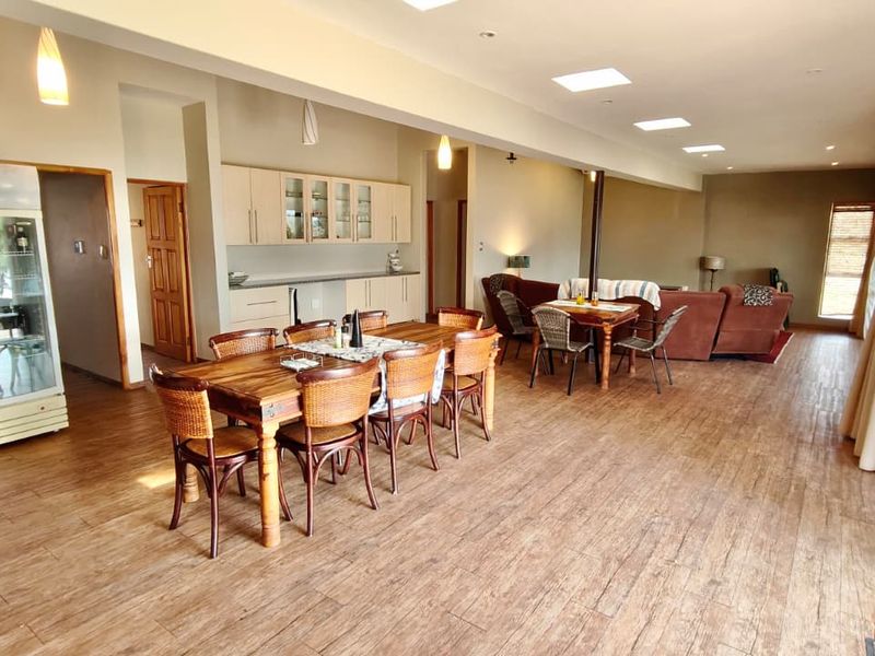 Spacious open-plan living and dining area featuring wood-look tile flooring, skylights, and built-in cabinetry, offering a bright and versatile layout.