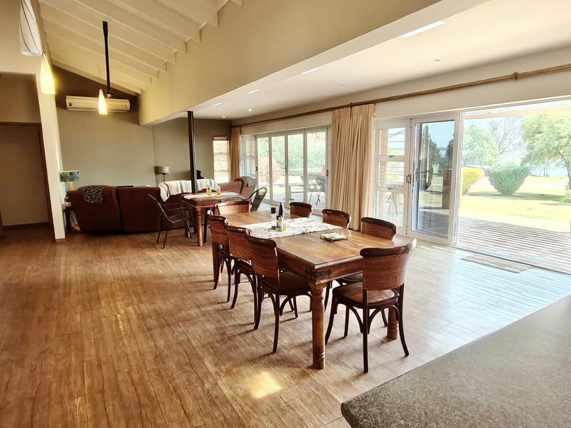 Spacious open-plan living and dining area featuring vaulted ceilings, laminate flooring, and large sliding glass doors providing seamless access to the outdoor garden space.