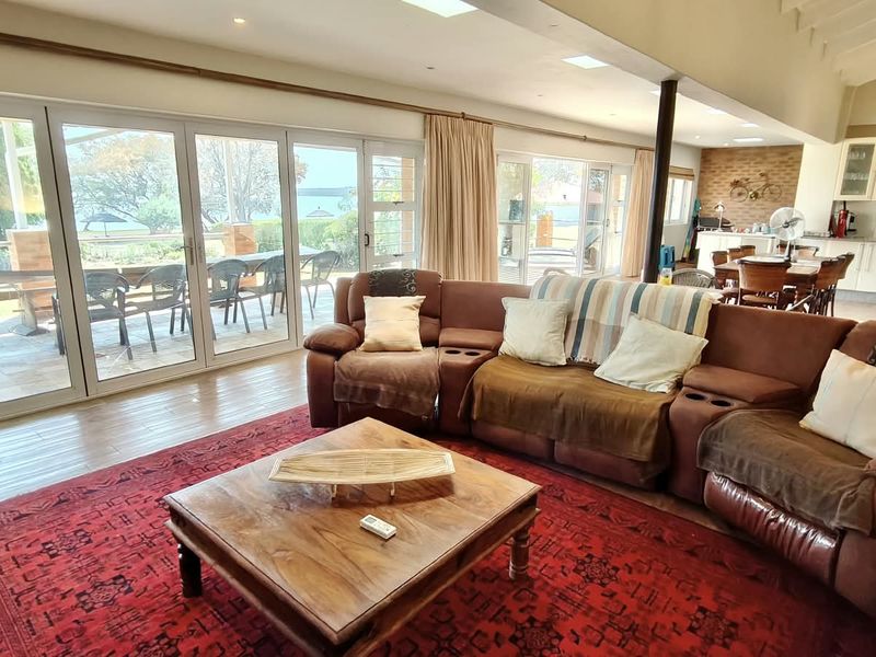 Spacious open-plan living and kitchen area featuring laminate flooring, extensive bi-fold doors for natural light, and direct access to the outdoor patio.