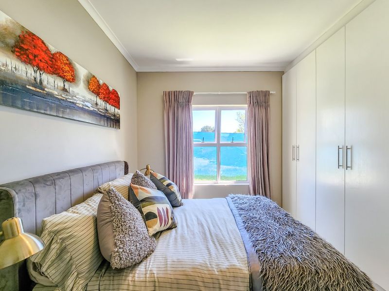 A well-maintained bedroom featuring built-in cupboards, neutral wall finishes, and a window providing natural light.