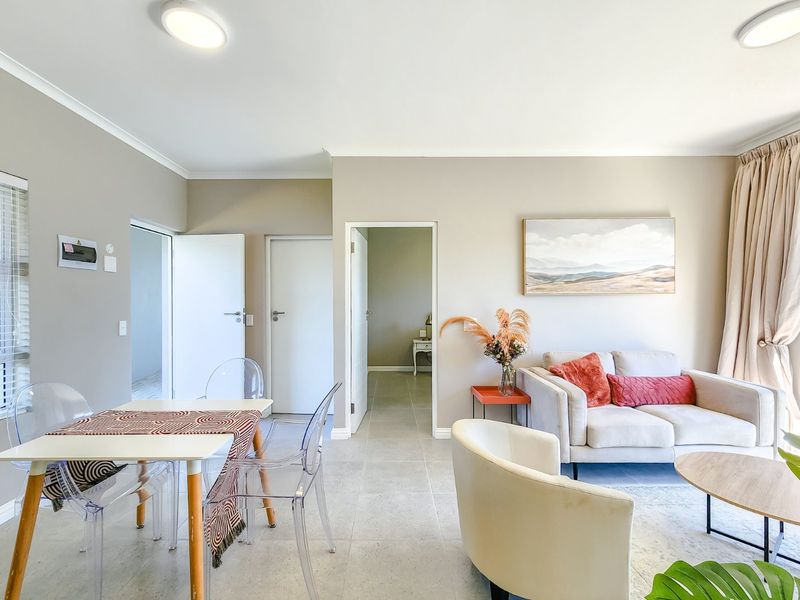 Bright open-plan living and dining area featuring neutral wall tones, tiled flooring, and multiple access points to adjacent rooms.