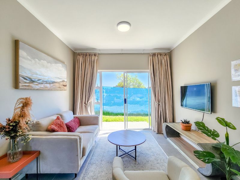 A bright and well-maintained living room featuring tiled flooring, a ceiling light fixture, and a large sliding glass door providing access to the outdoors.