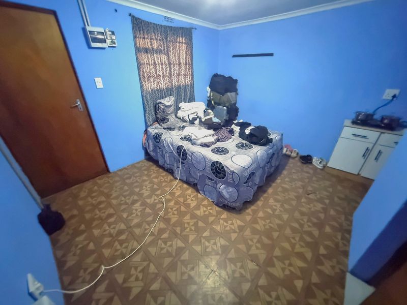 A bedroom featuring vinyl flooring and a small built-in cabinet unit, currently requiring cosmetic updates and improved electrical finishing.