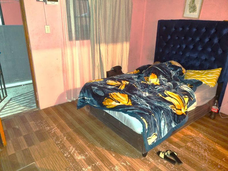 A bedroom featuring laminate flooring and direct access to an exterior area, requiring cosmetic updates to the wall finishes and flooring.