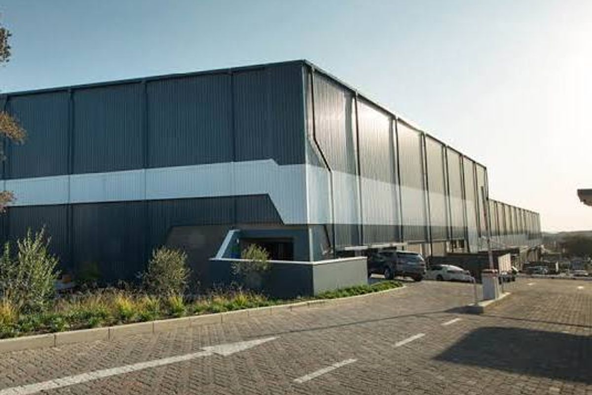 A modern industrial warehouse facility featuring corrugated metal cladding, a paved driveway, and landscaped exterior grounds.