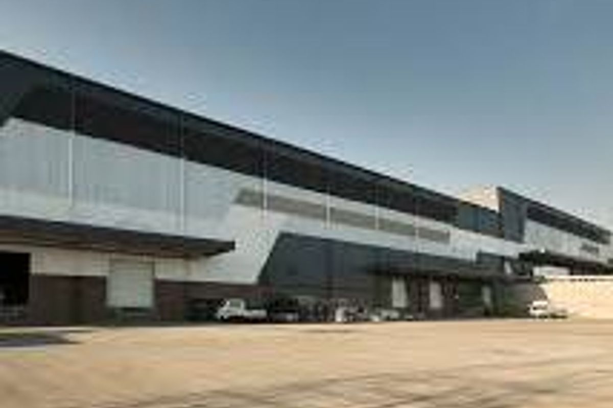 Modern industrial warehouse facility featuring extensive loading docks, roller shutter doors, and a spacious concrete yard for logistics operations.