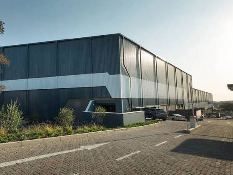 A modern industrial warehouse facility featuring corrugated metal cladding, a paved driveway, and landscaped exterior grounds.