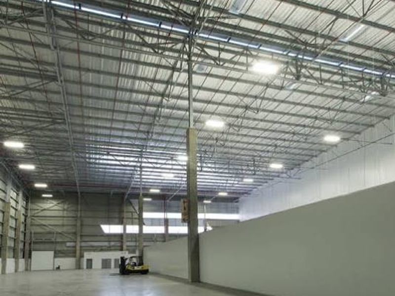 Spacious industrial warehouse interior featuring high-clearance ceilings, exposed steel trusses, polished concrete flooring, and efficient high-bay lighting.