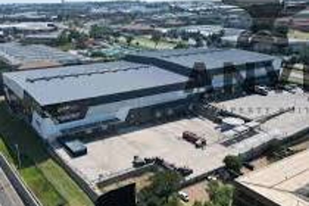 Aerial view of a large industrial warehouse facility featuring extensive loading bays and a paved yard area within a commercial business park.