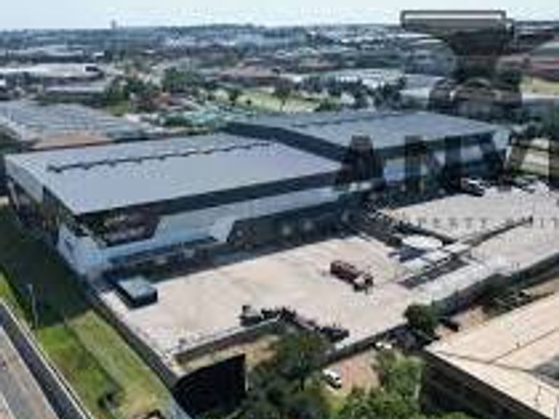 Aerial view of a large industrial warehouse facility featuring extensive loading bays and a paved yard area within a commercial business park.