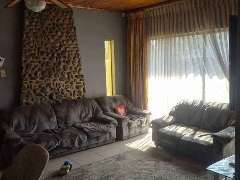 Living room featuring a prominent stone fireplace, timber ceiling, and large sliding glass doors providing natural light.