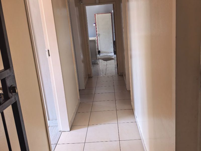 A functional hallway featuring tiled flooring and a timber-paneled ceiling, providing access to multiple rooms within the home.