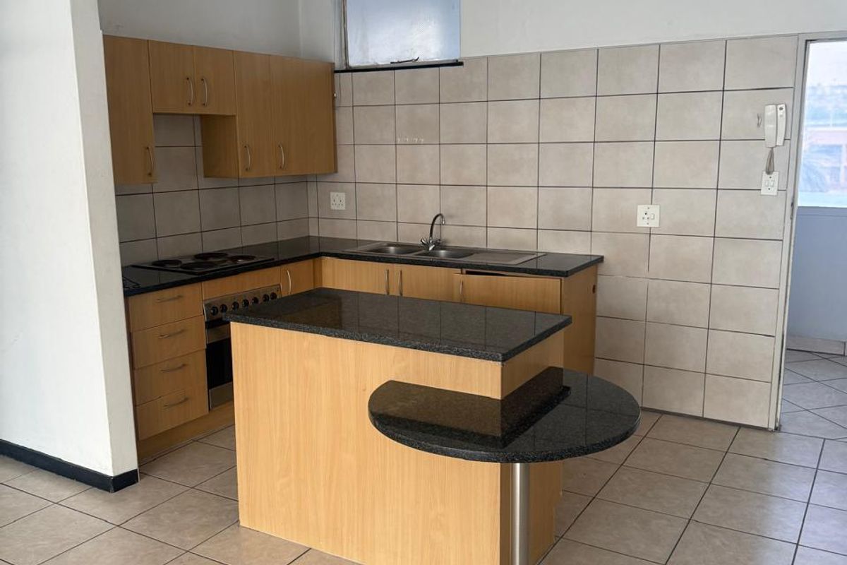 Functional kitchen featuring laminate cabinetry, granite countertops, built-in oven, electric hob, and a breakfast nook, finished with neutral ceramic wall and floor tiles.
