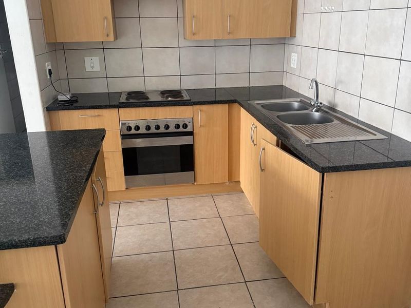 Functional kitchen featuring light wood cabinetry, granite countertops, tiled backsplash, and built-in oven with hob, offering a practical layout for daily use.