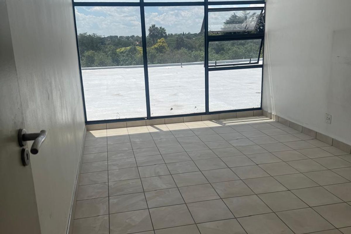 An empty bedroom featuring large windows with natural light, tiled flooring, and a ceiling light fixture, offering a blank canvas for personalization.