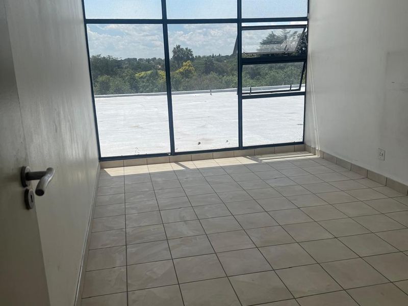 An empty bedroom featuring large windows with natural light, tiled flooring, and a ceiling light fixture, offering a blank canvas for personalization.