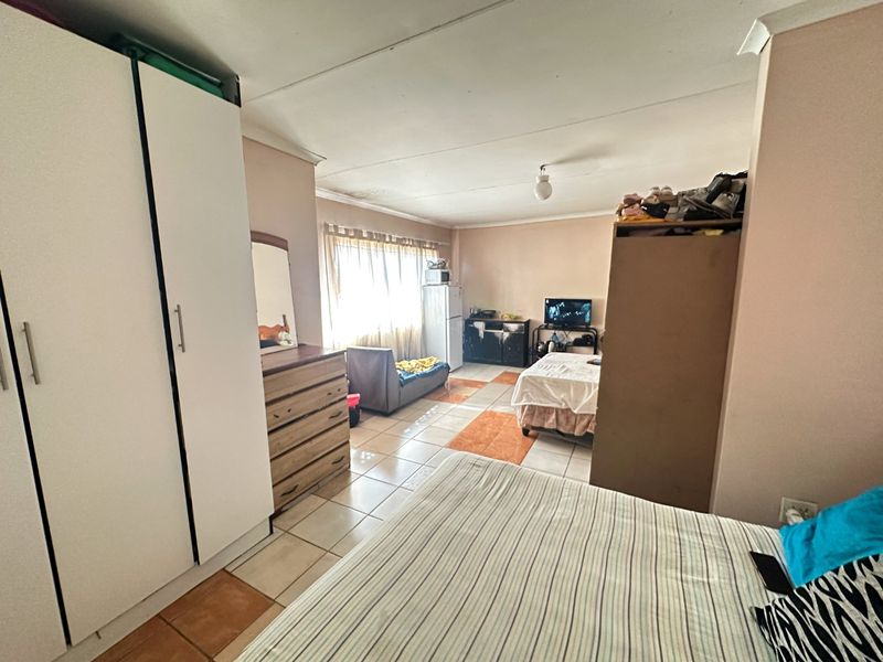 A bedroom featuring tiled flooring and a built-in wardrobe, offering a functional space that could benefit from cosmetic updates and improved layout.