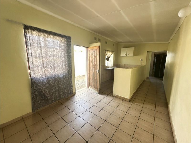 An open-plan living and kitchen area featuring tiled flooring, built-in cabinetry, and direct access to the exterior.