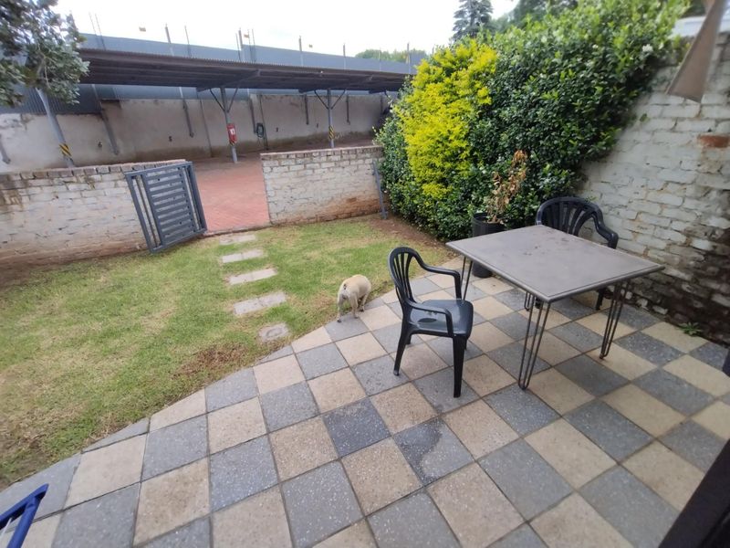 A private outdoor patio area featuring checkered paving, a small lawn, and brick boundary walls, providing a functional space for outdoor relaxation.