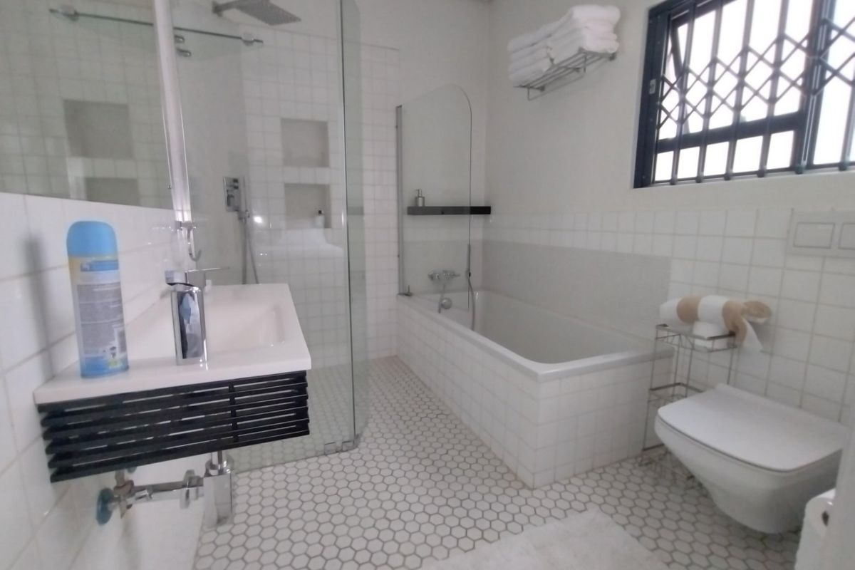 Modern bathroom featuring a wall-mounted vanity, glass-enclosed shower, built-in bathtub, and wall-hung toilet with contemporary hexagonal floor tiling.