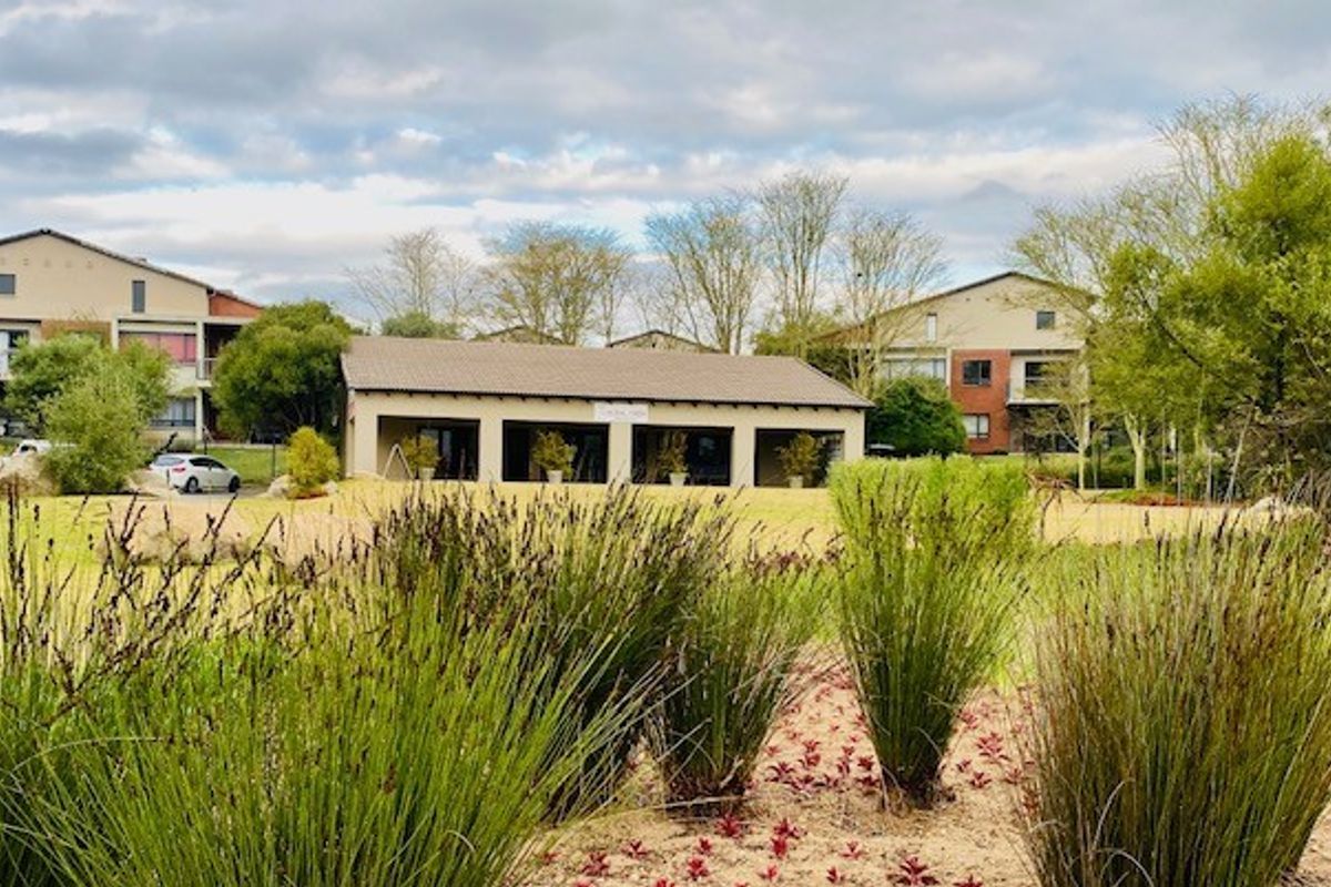 A view of the landscaped communal garden area and shared building facilities within the apartment complex grounds.