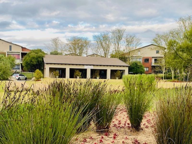 A view of the landscaped communal garden area and shared building facilities within the apartment complex grounds.