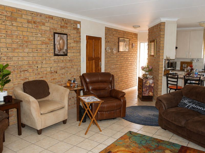 Open plan living area featuring exposed brick walls, ceramic tiled flooring, and an adjoining kitchen with granite countertops and cabinetry.