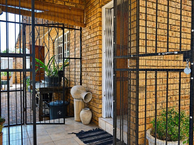 A secure entrance area featuring exposed brickwork, tiled flooring, and heavy-duty security gates providing access to the townhouse.