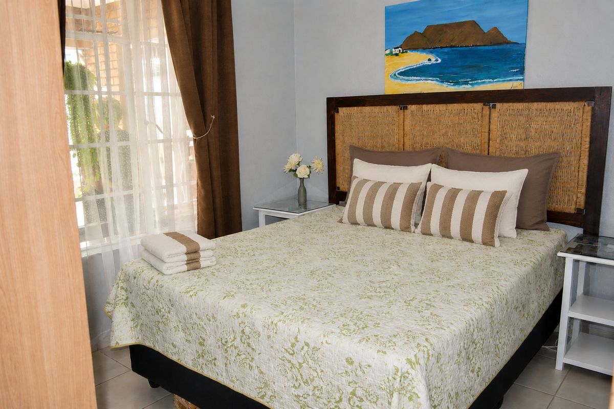 A well-maintained bedroom featuring tiled flooring and a window with security bars, offering a comfortable and functional living space.