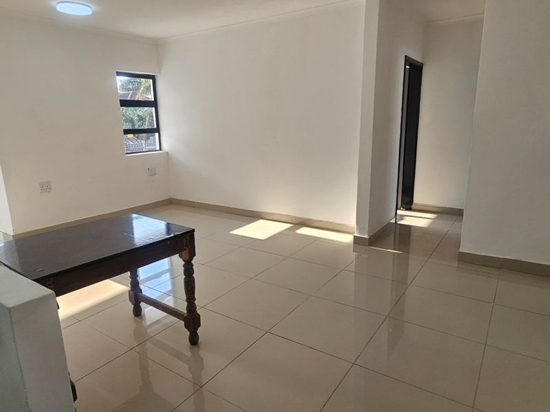Spacious open-plan living area featuring neutral tiled flooring, clean white walls, and natural light, providing a versatile blank canvas for interior design.