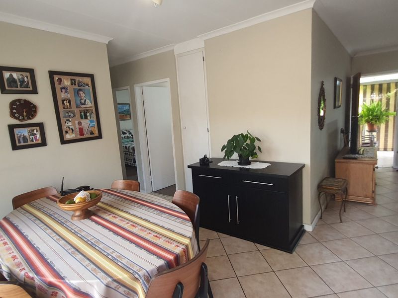 A view of the dining and living area featuring tiled flooring and a built-in storage cupboard, leading towards a rear patio.