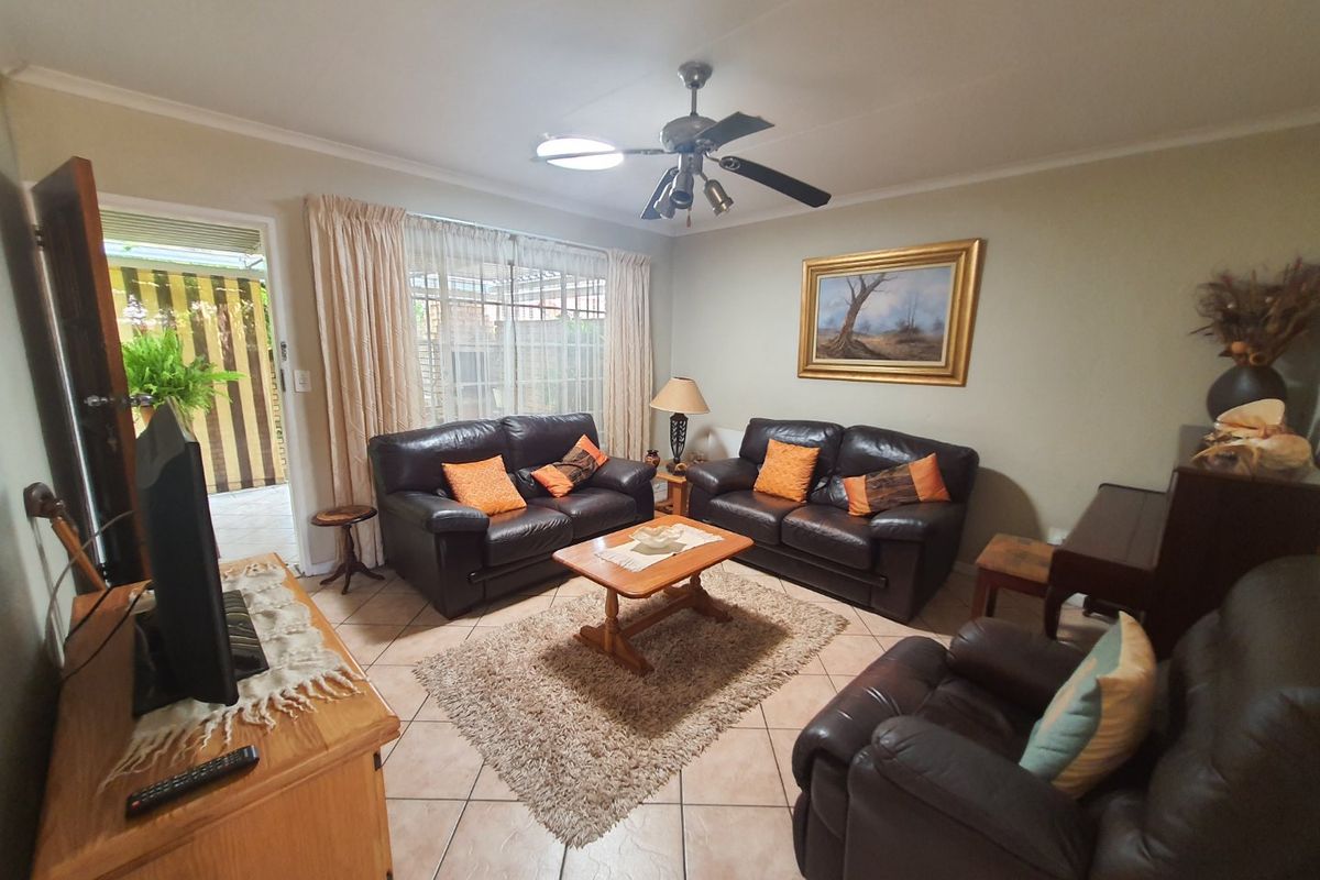 A comfortable living room featuring tiled flooring, a ceiling fan, and direct access to an outdoor patio area through a sliding glass door.